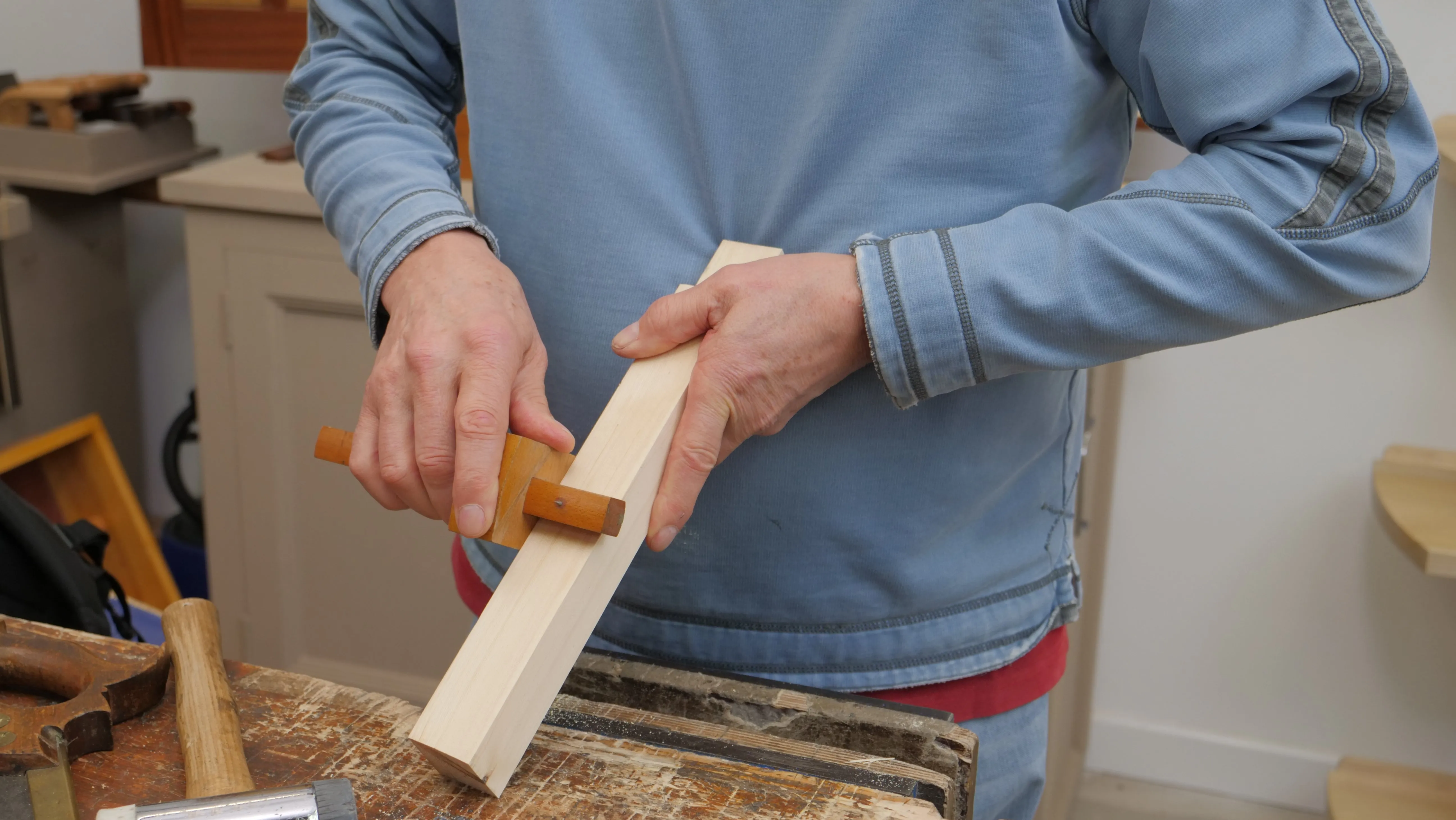 Hold your wood with one hand and use the other to pull the gauge. You can also put your wood in a vise if this is easier