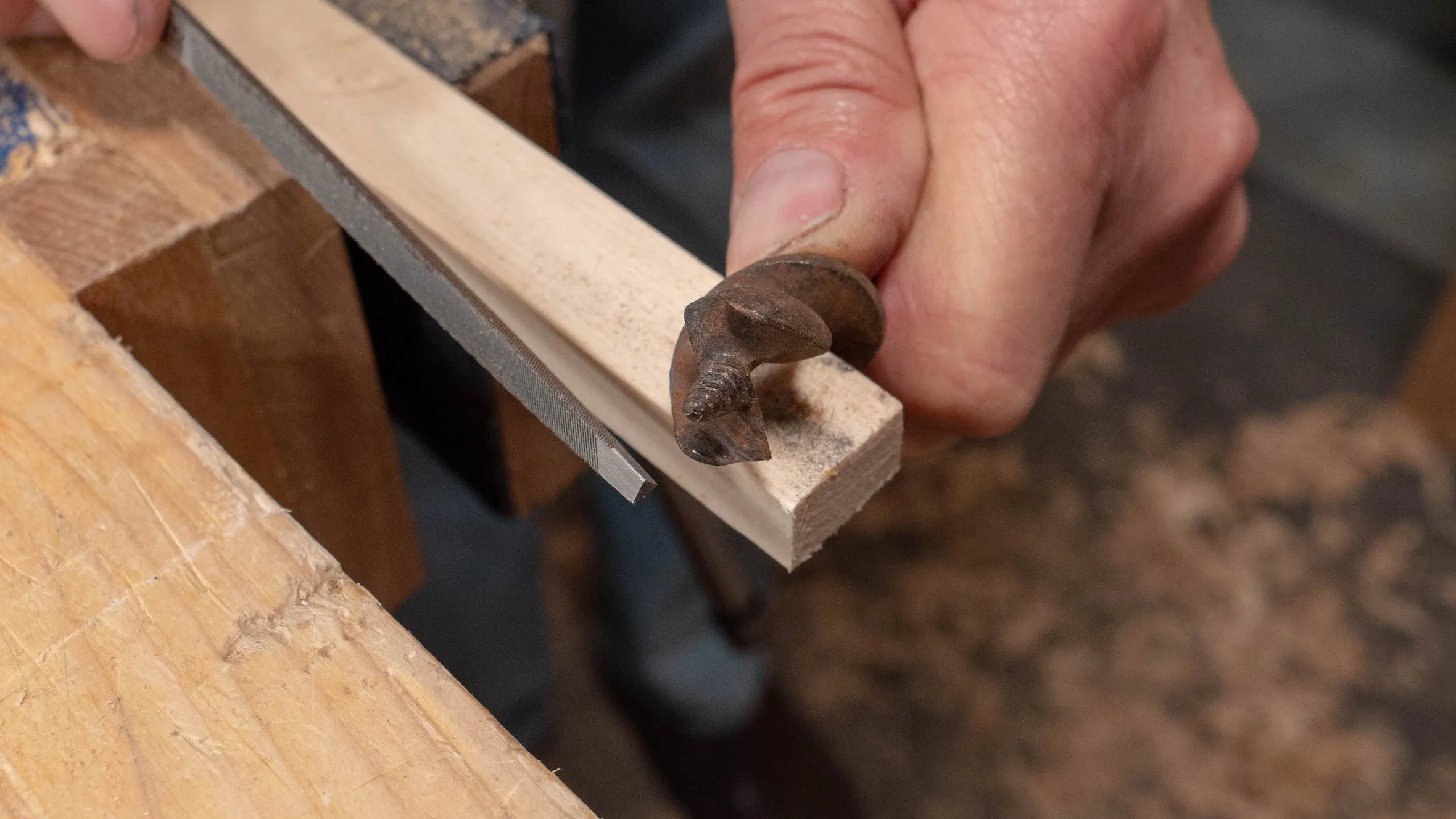 Rest your bit onto something so you can apply downward pressure when filing the spur